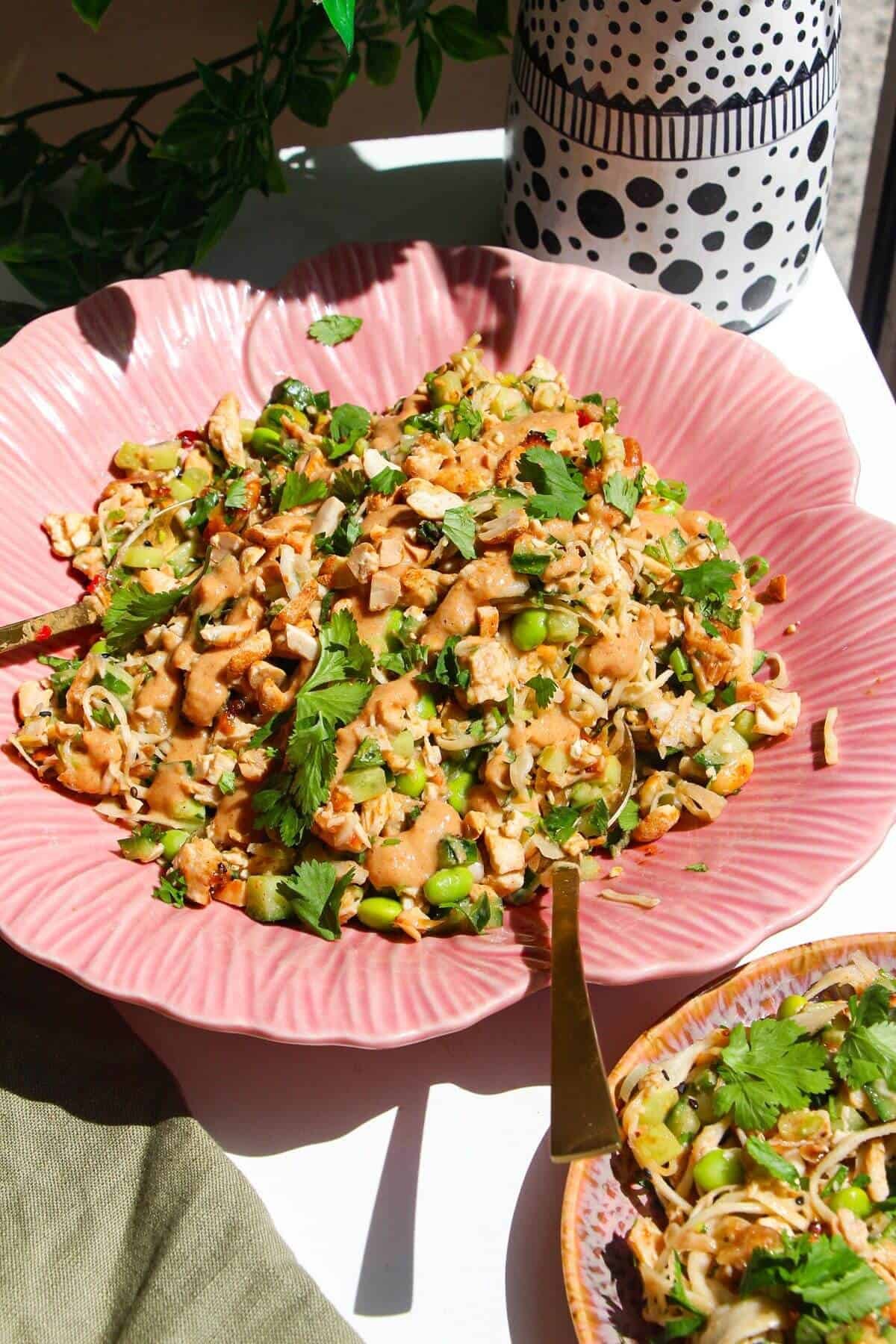 Satay chicken crunch salad in serving bowl with spoon.