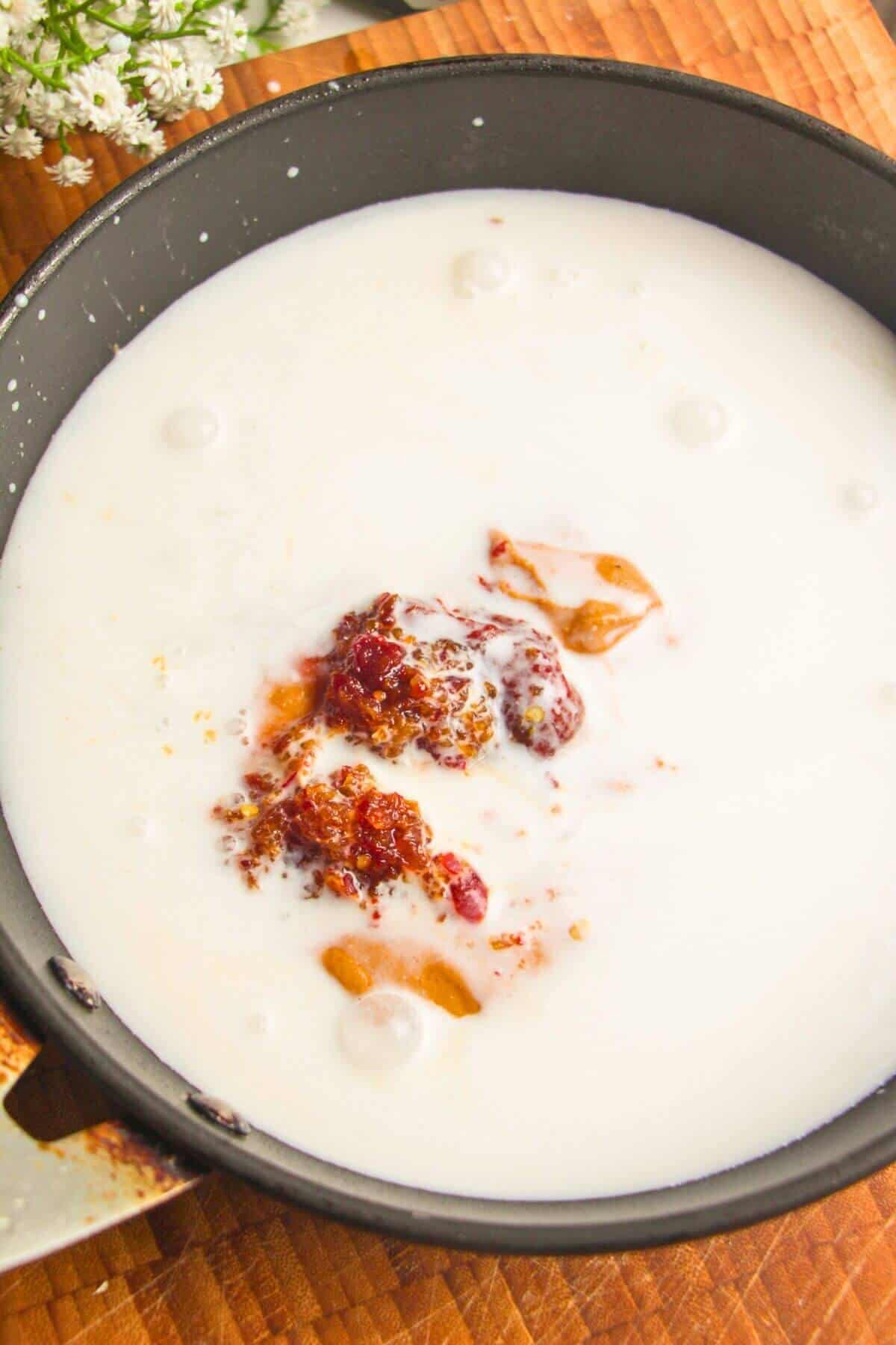 Peanut butter, gochujang paste and coconut milk in a pan.