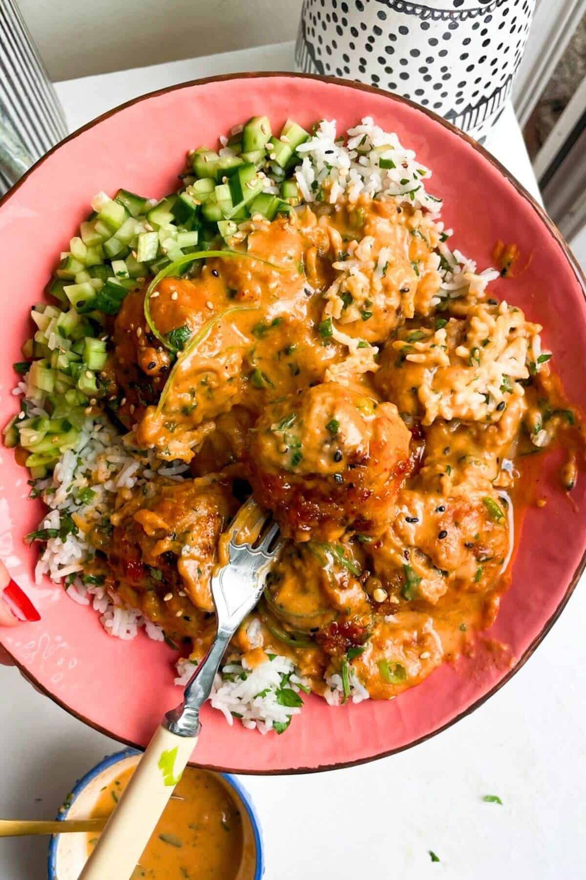 Satay chicken meatballs with rice in a pink bowl.