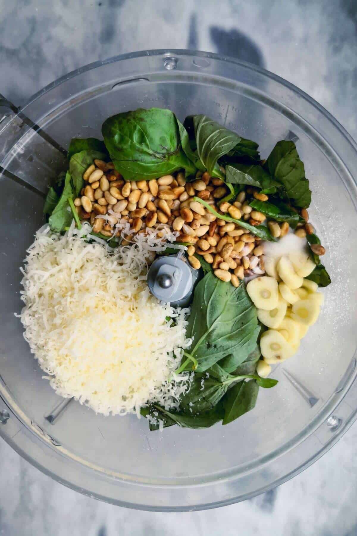 Ingredients for basil pesto in the bowl of a food processor.