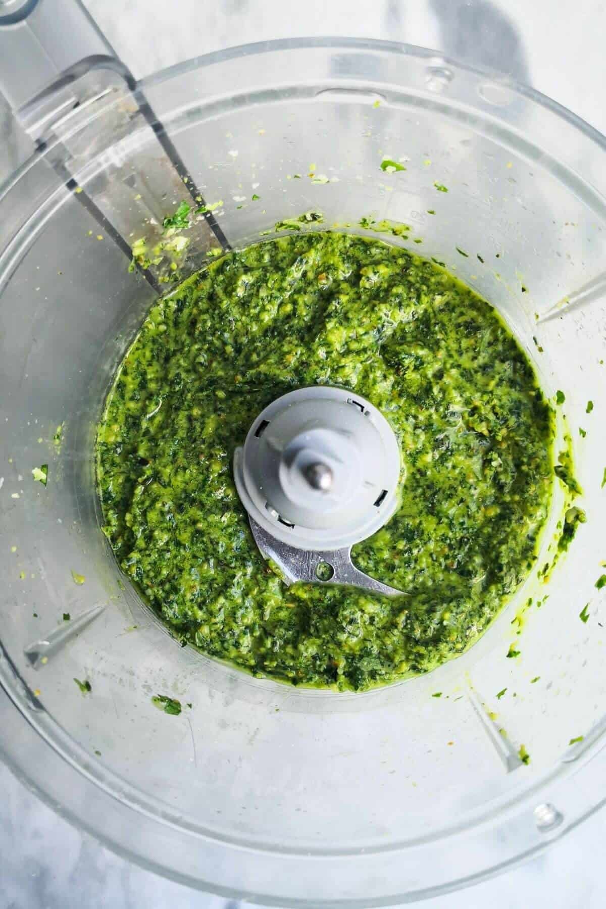 Blitzed basil pesto in the bowl of a food processor.