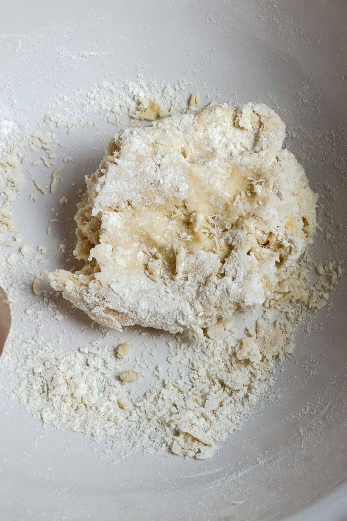 Crumbly pasta dough in a white mixing bowl.