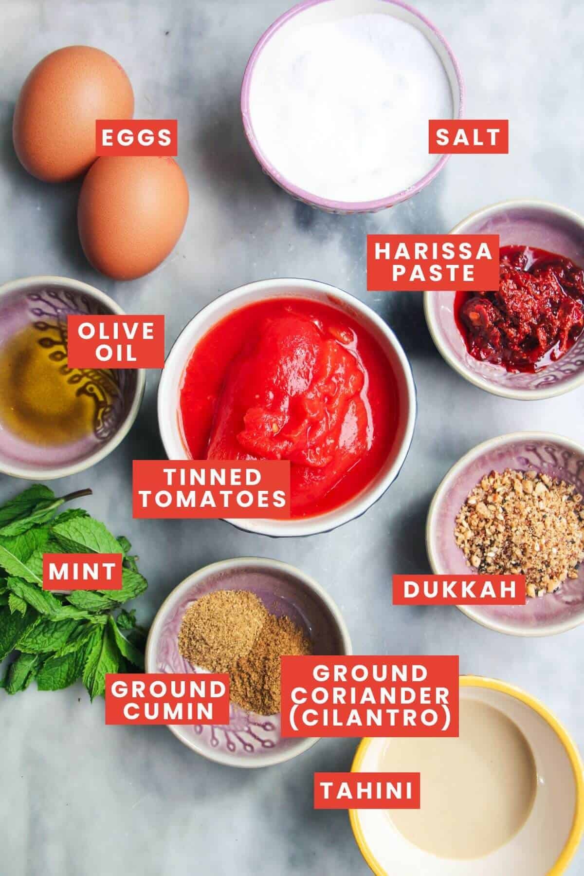 Ingredients for shakshuka laid out on a grey marble background and labelled.
