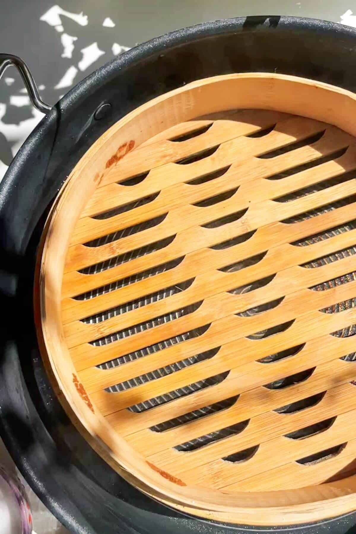 Bamboo steamer basket inside a large pan.