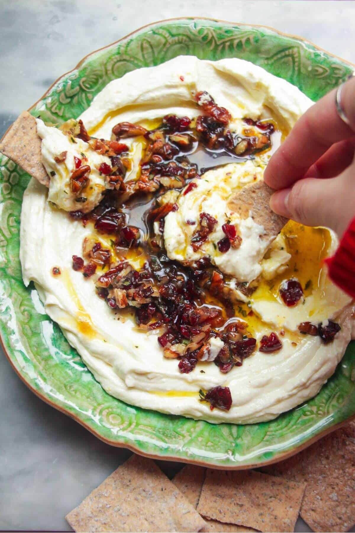 Whipped feta dip on a small green plate, topped with oil and nuts.