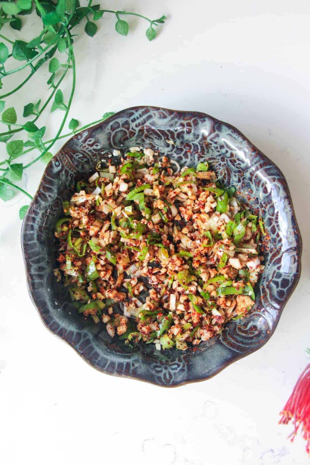 Sizzling oil ingredients in a small black patterned bowl.