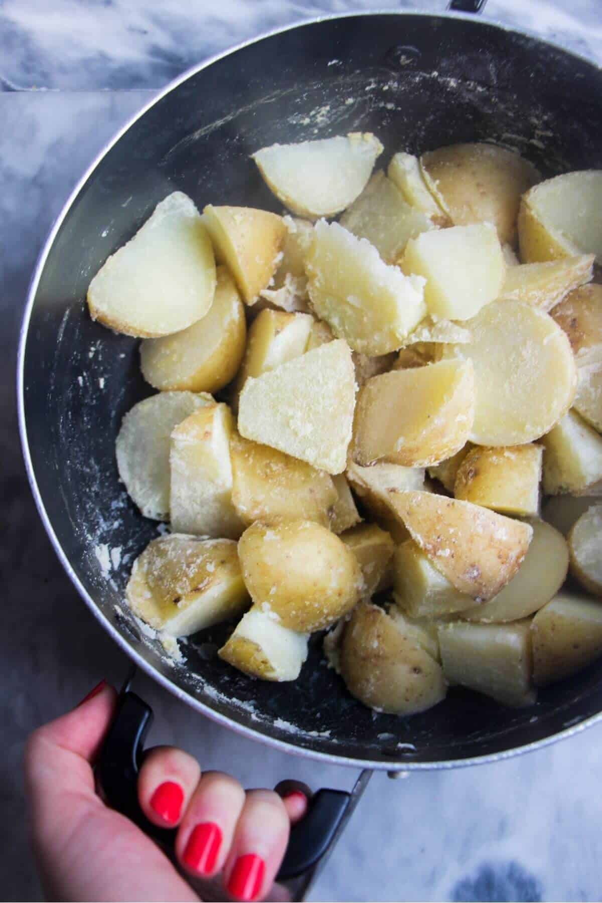 Hand shaking pot with potatoes and polenta.