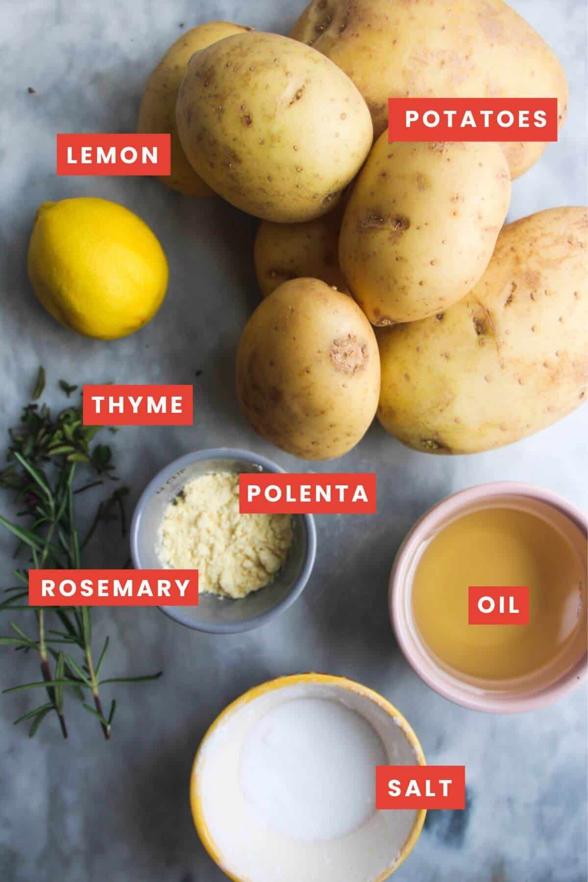 Ingredients for crispy skin on roast potatoes laid out on a grey marble background and labelled.