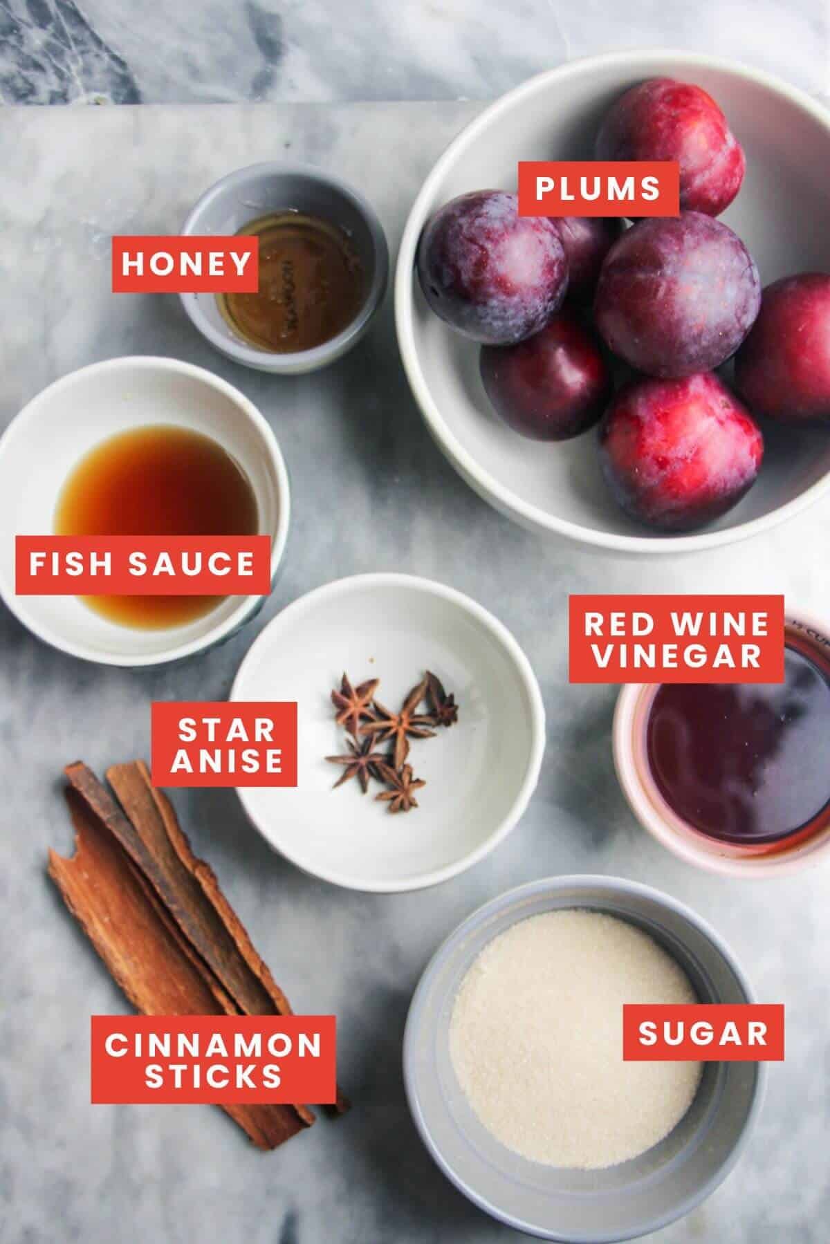 Ingredients for sticky plum sauce laid out on a grey marble background and labelled.