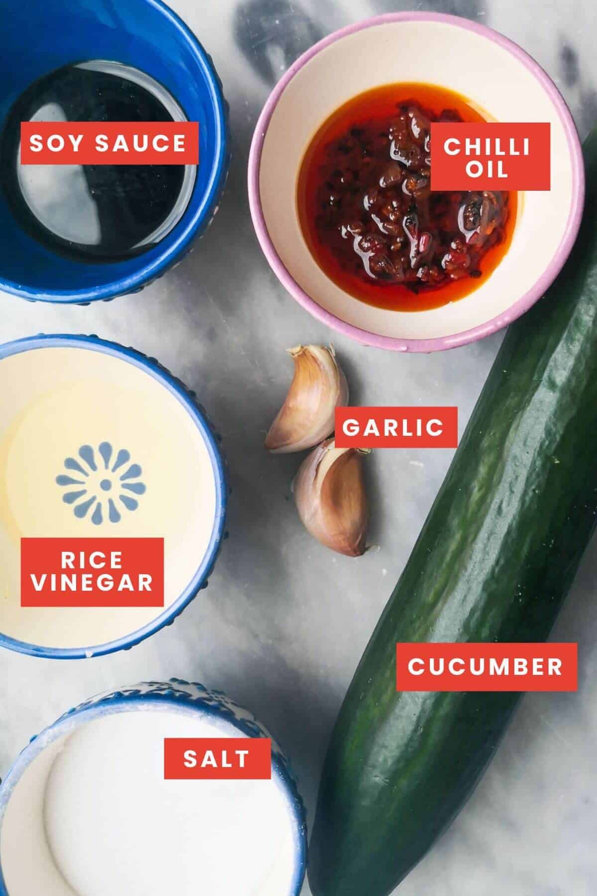 Smacked cucumber salad ingredients on a grey marble background.