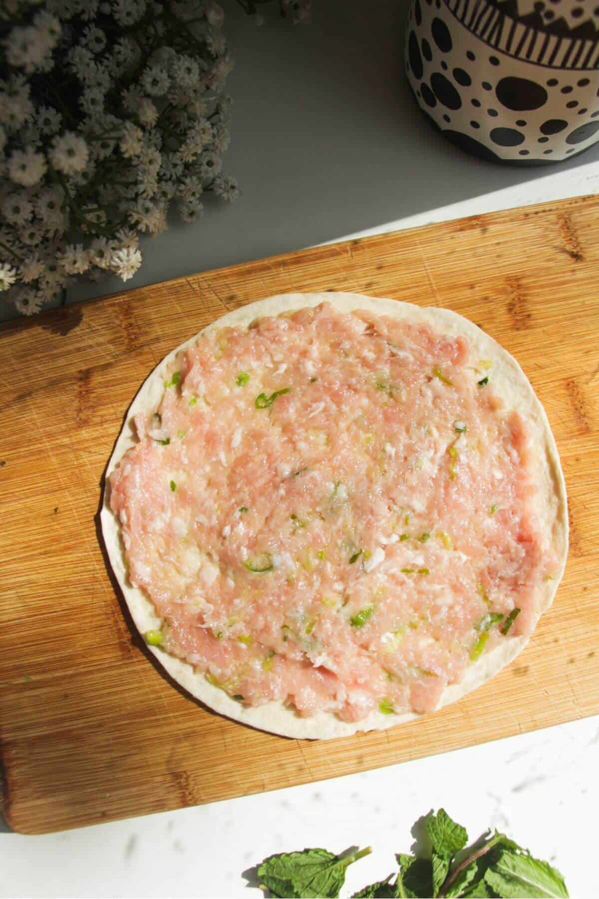 Chicken topping spread onto mini tortilla.