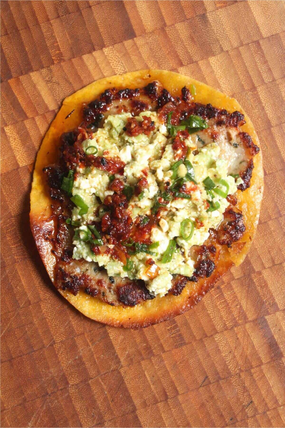 Smash sausage taco topped with smashed avocado, feta and chilli oil.