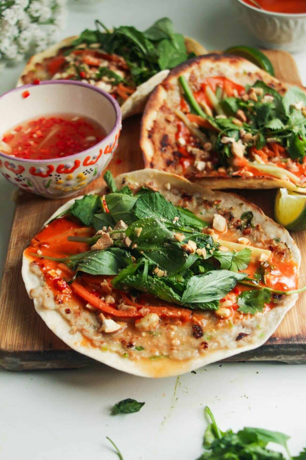 Three chicken banh mi tacos on a wooden board.