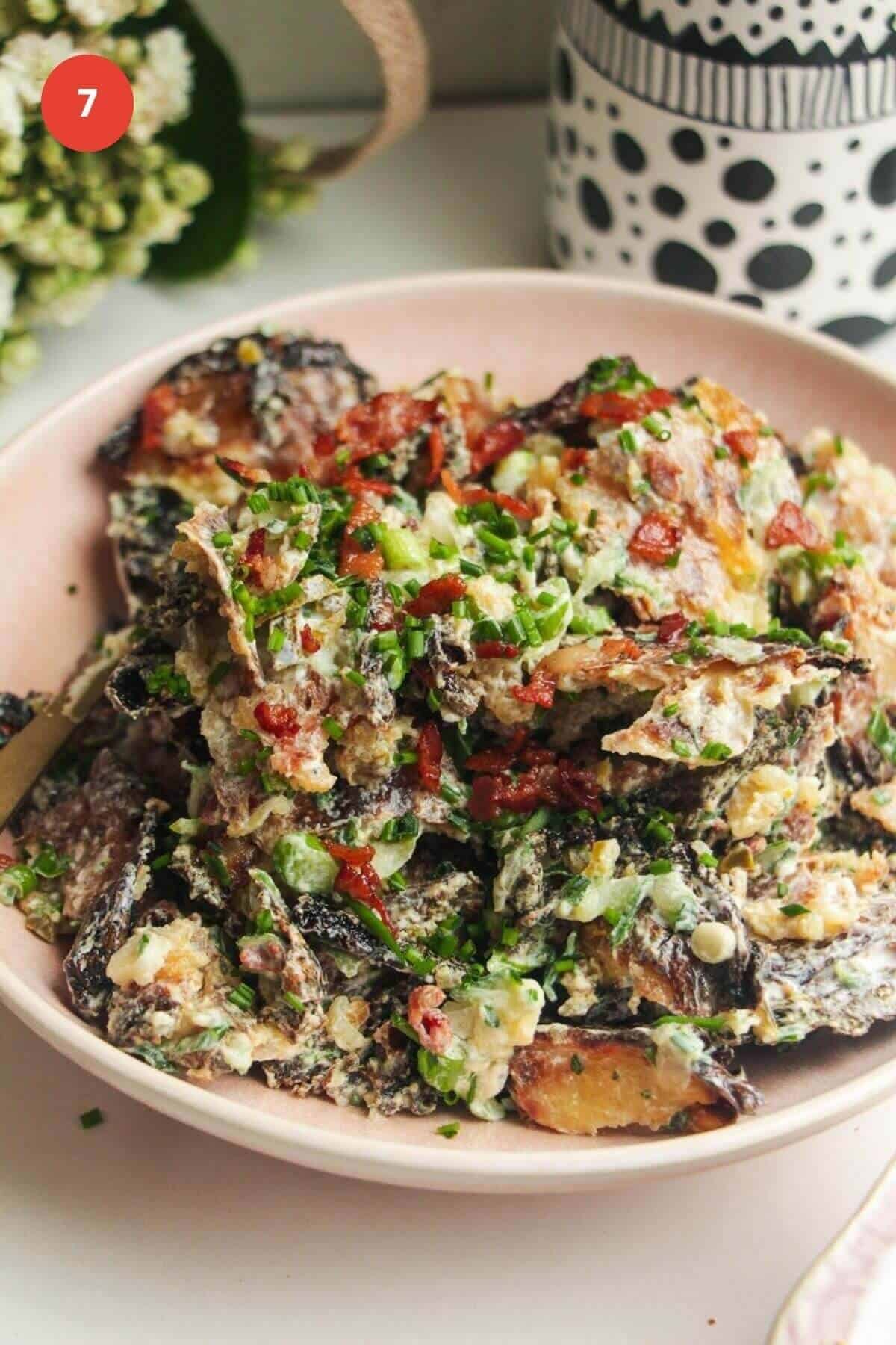 Smashed potato salad in serving bowl, with a spoon.