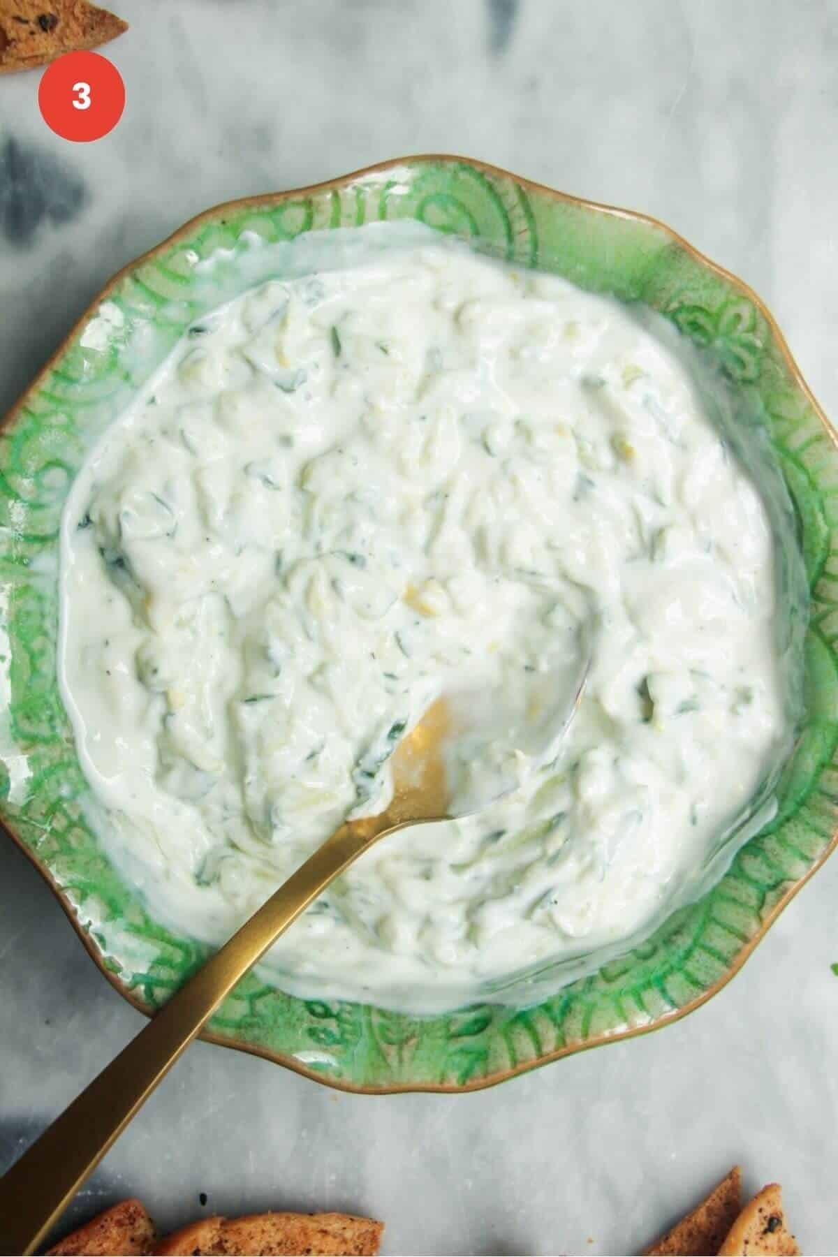 Spoon in a bowl with tzatziki sauce.