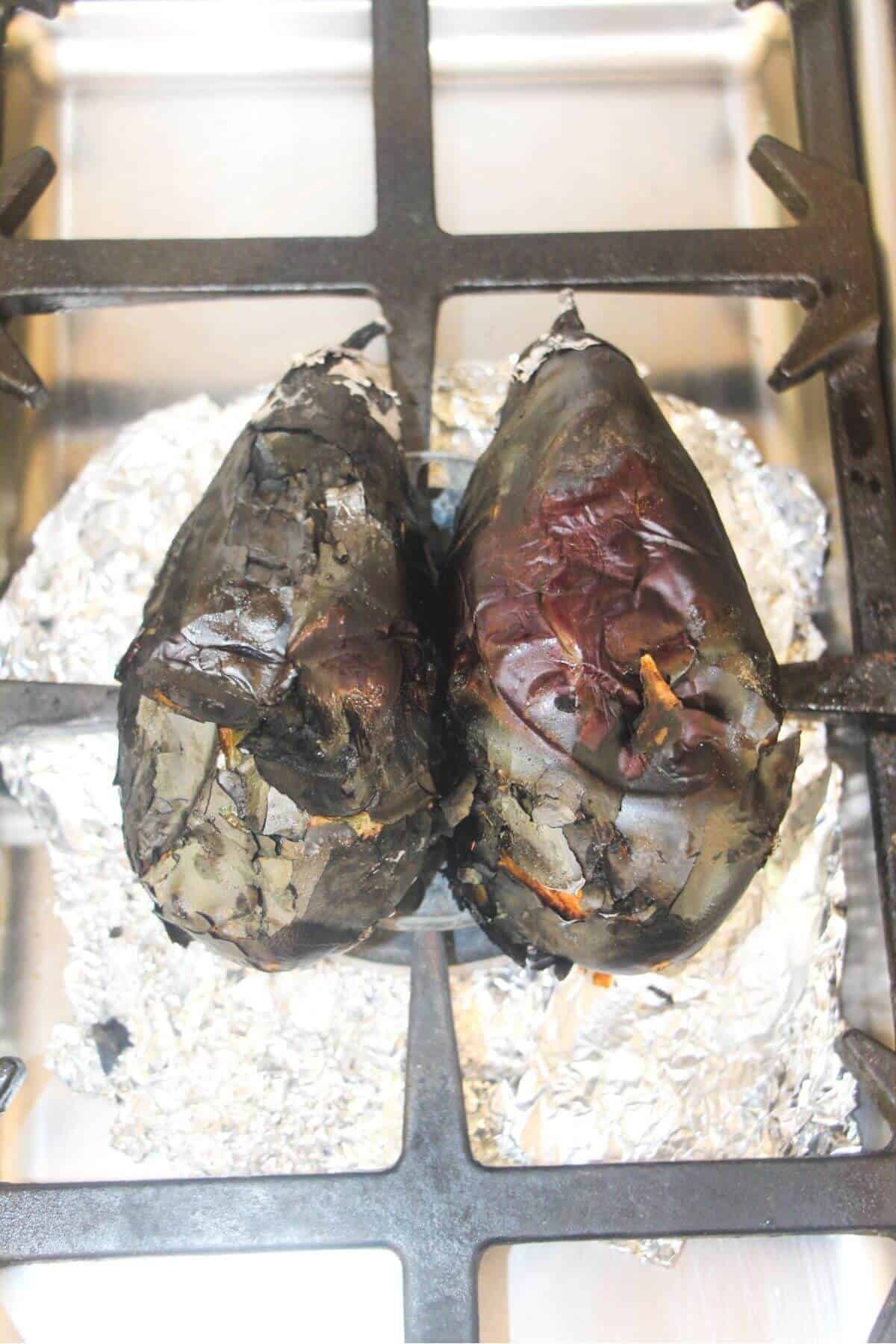 Two eggplants on top of a gas hob.