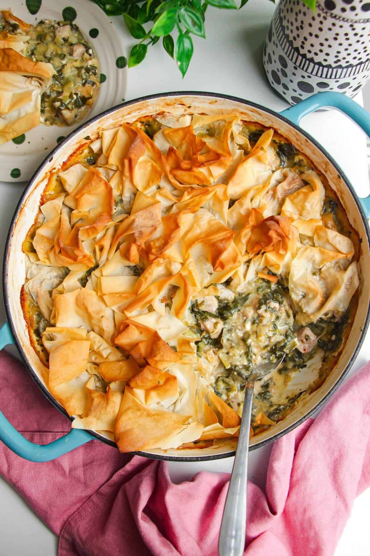 Spanokopita chicken pot pie, with a serving spoon in the pan.