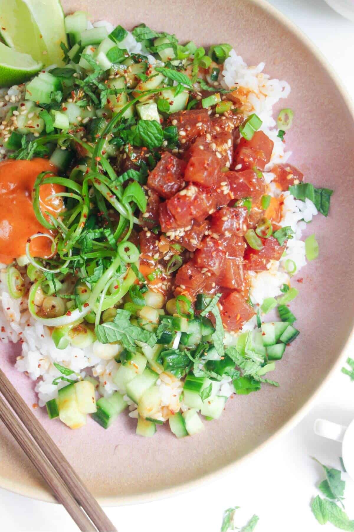 Diced tuna and cucumber on rice in a pink bowl.