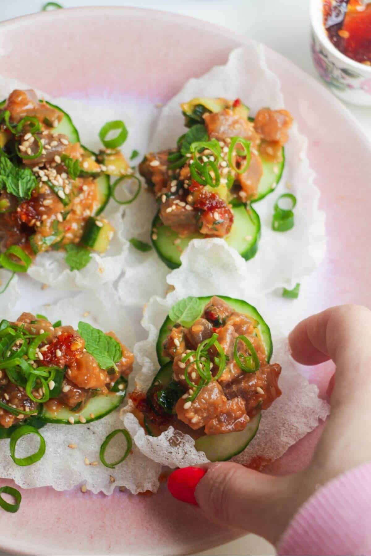 Four tuna rice paper cups on a pink plate.