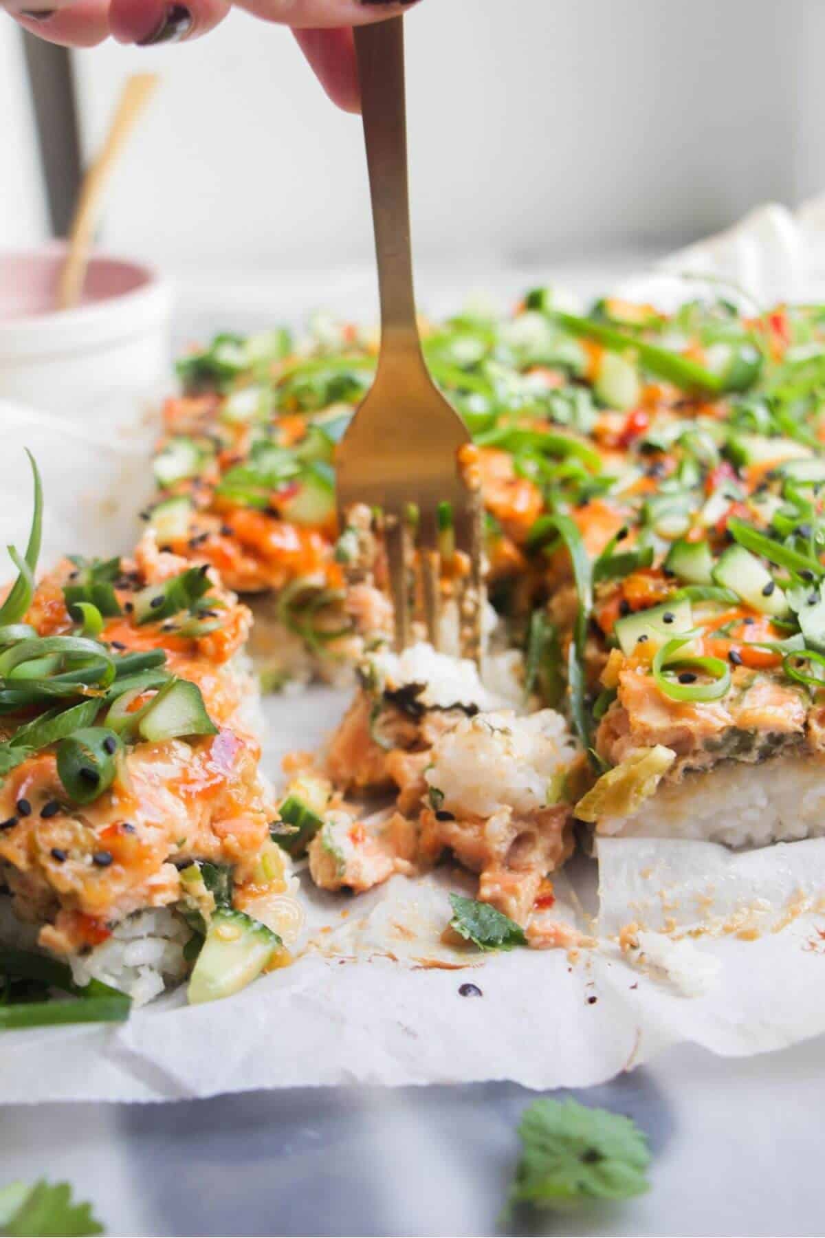 A fork piercing into a piece of salmon sushi bake.