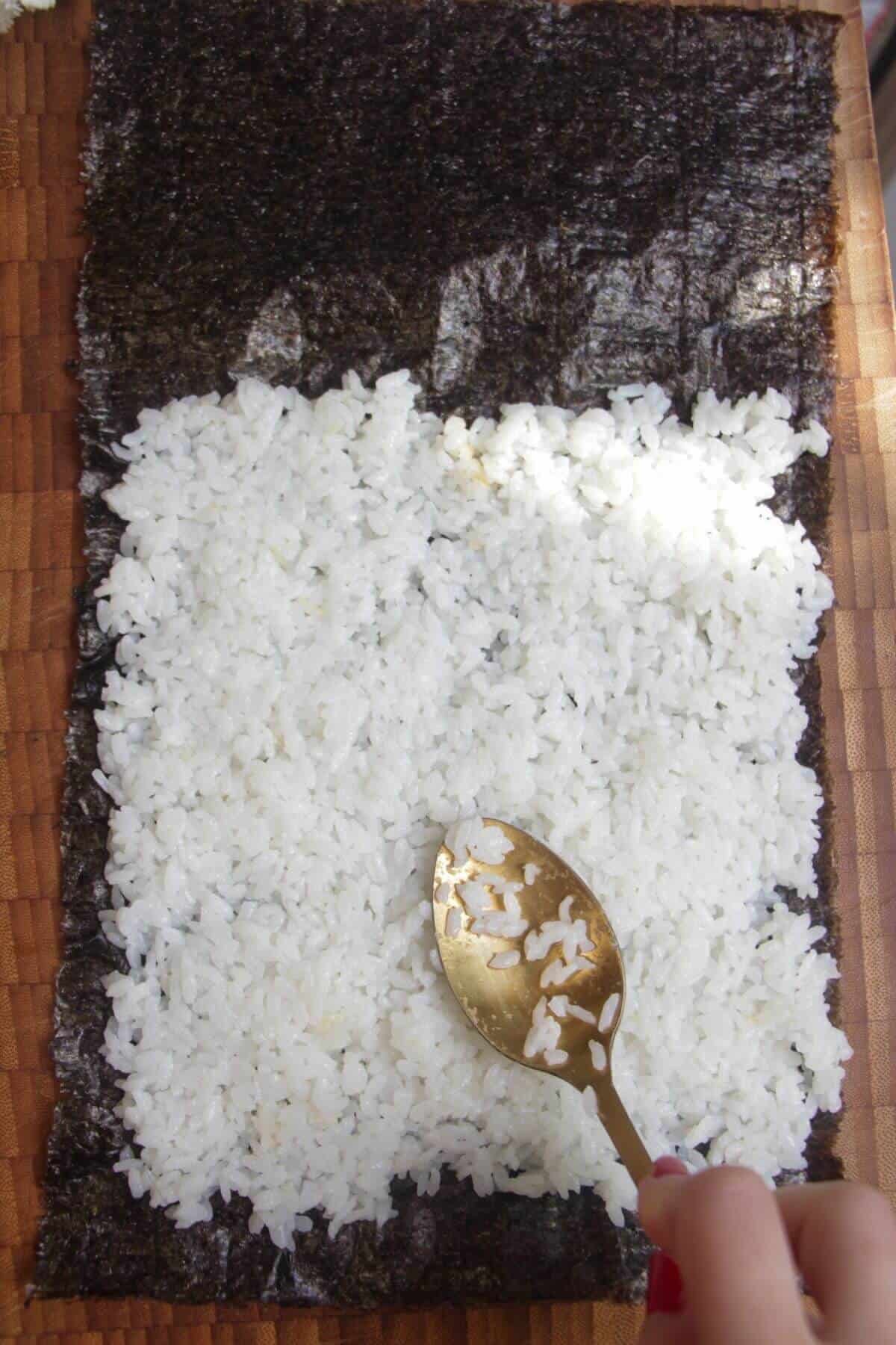 Spreading sushi rice onto seaweed sheet.