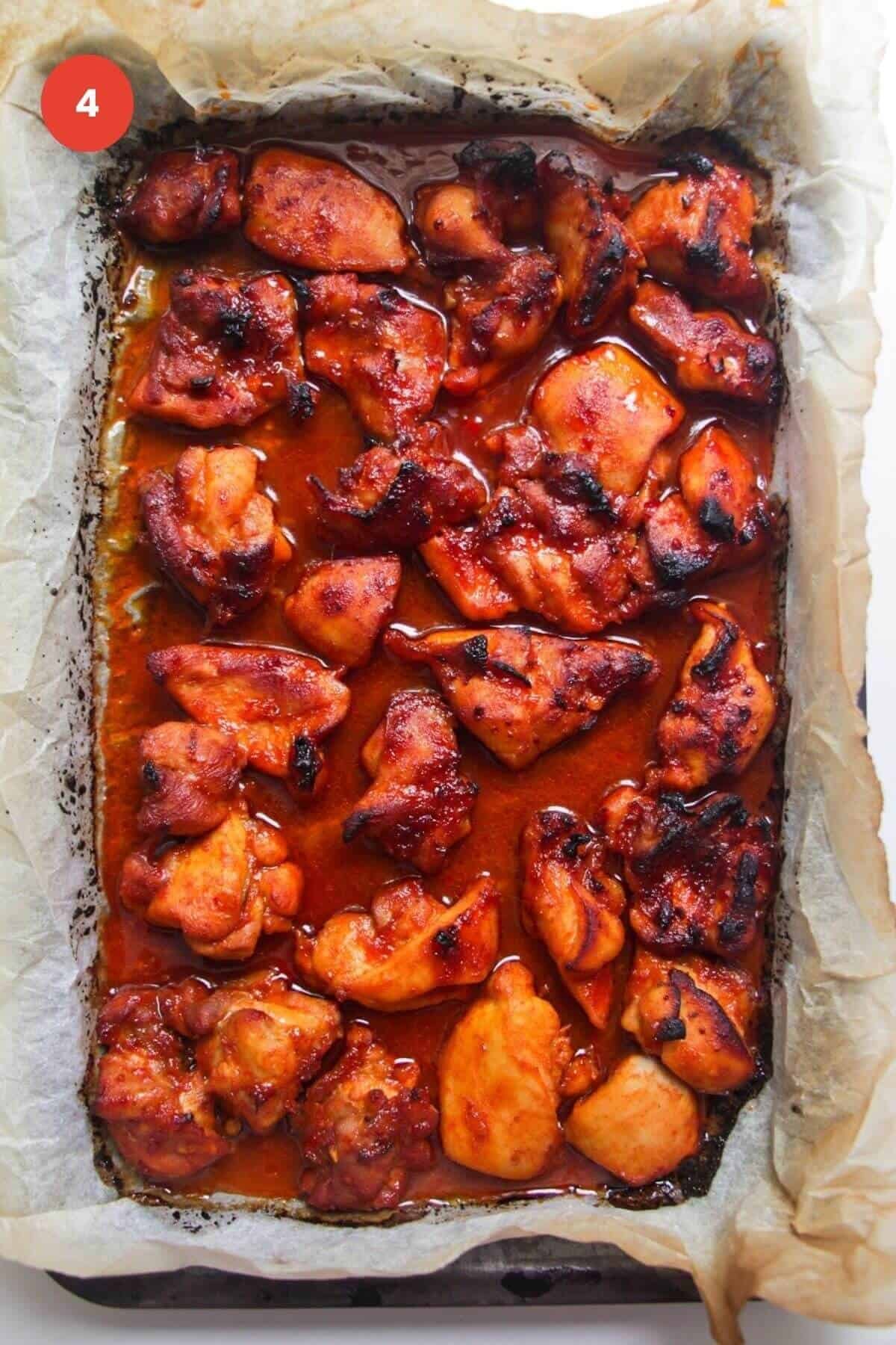 Cooked, charred gochujang chicken on oven tray.