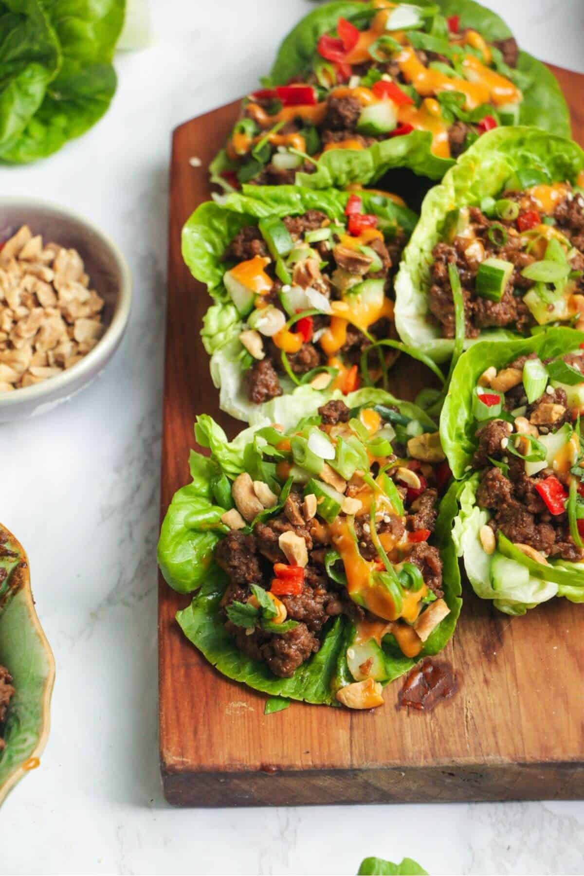 Korean beef lettuce wraps on a wooden board, with lettuce on the side.