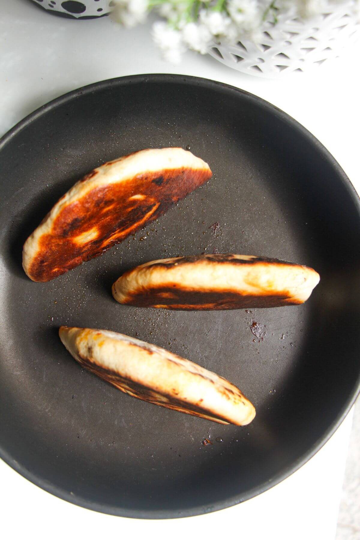 Three stuffed flatbreads in a small pan.