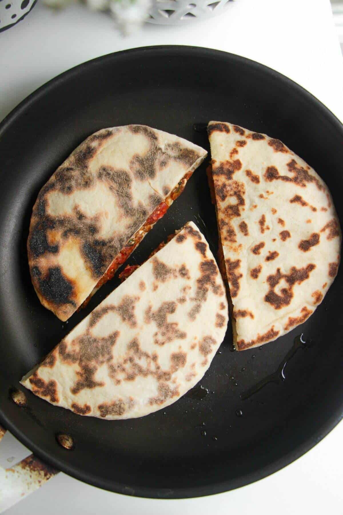 Three stuffed flatbreads in a small pan.