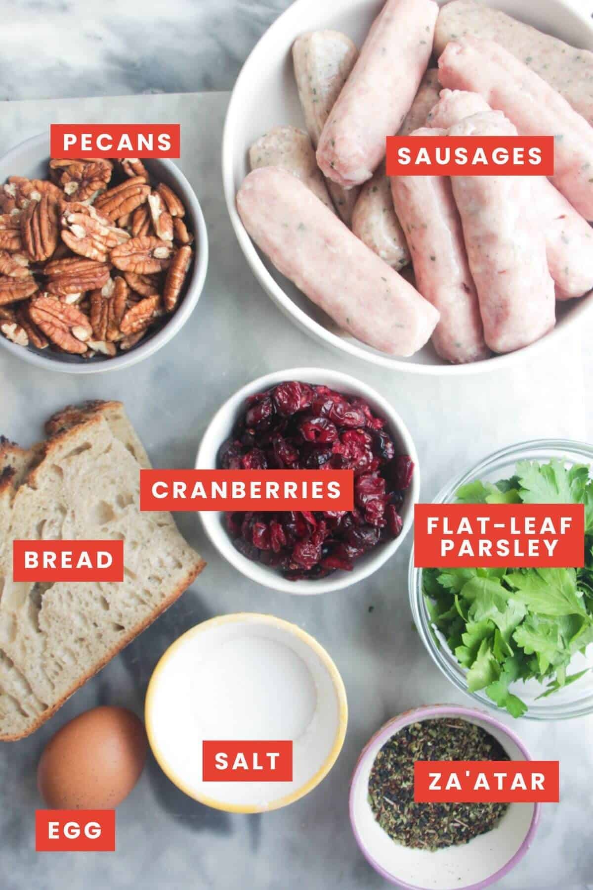 Ingredients for cranberry pecan stuffing balls laid out on a grey marble background.