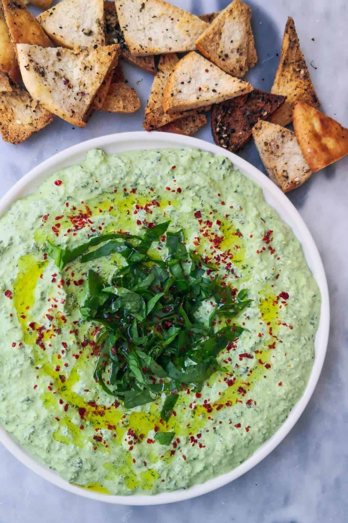 Spinach and feta dip on a small white plate with pita chips.