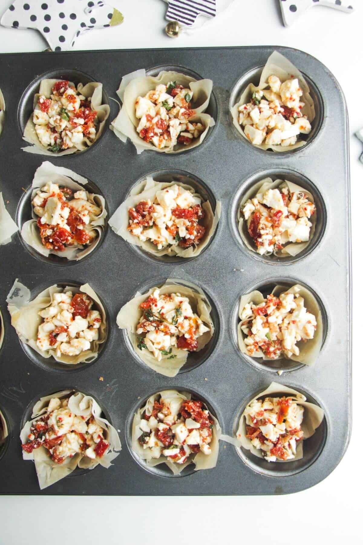 Sundried tomato feta filo cups, unbaked in a mini muffin tin.