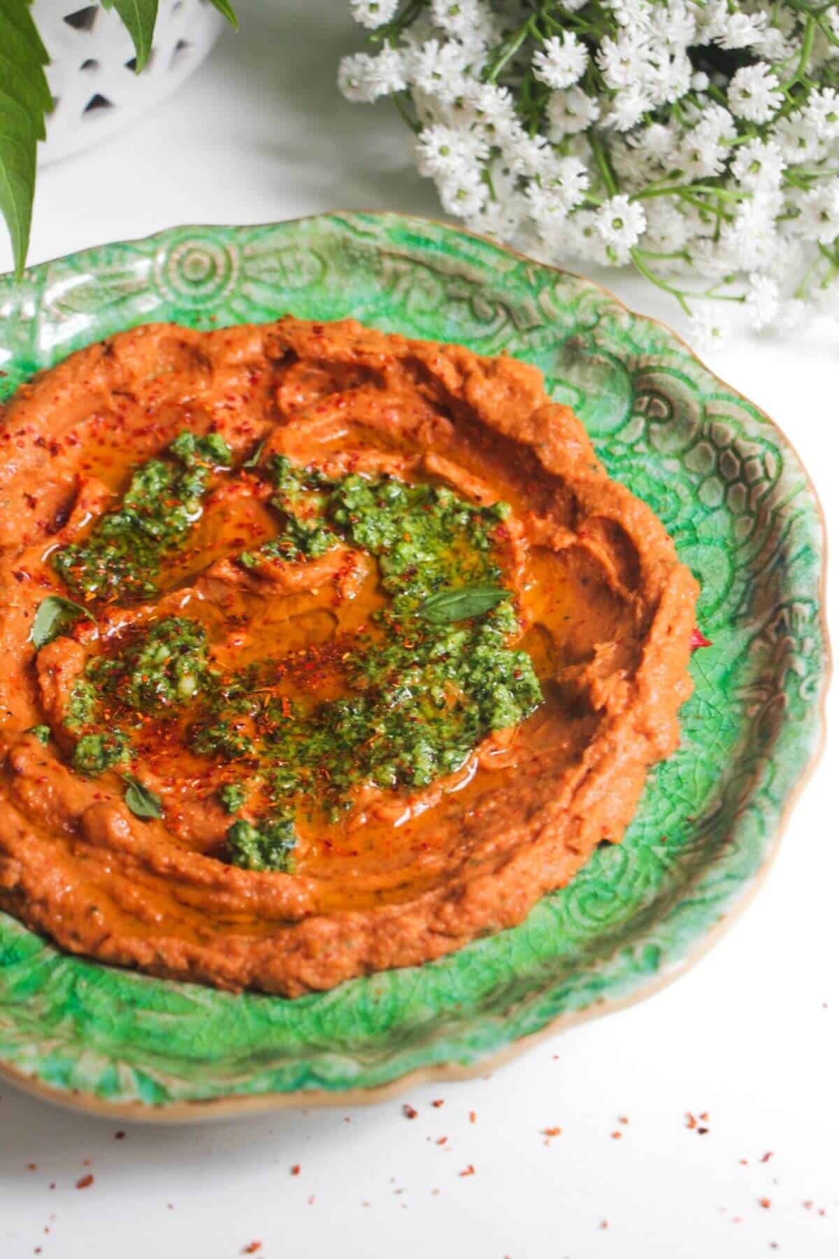 Sundried tomato basil hummus on a green plate.