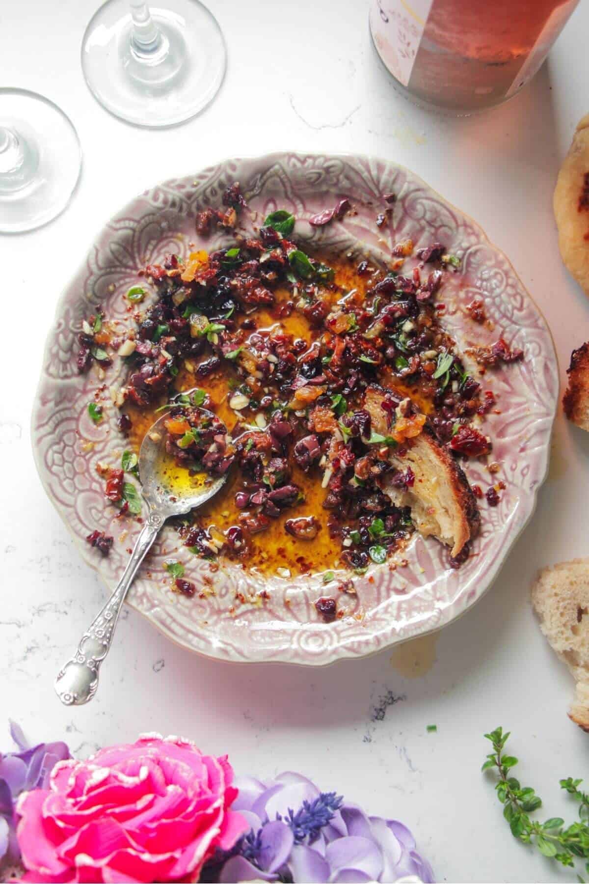 Date night bread dipping oil on a pink plate with a silver spoon.