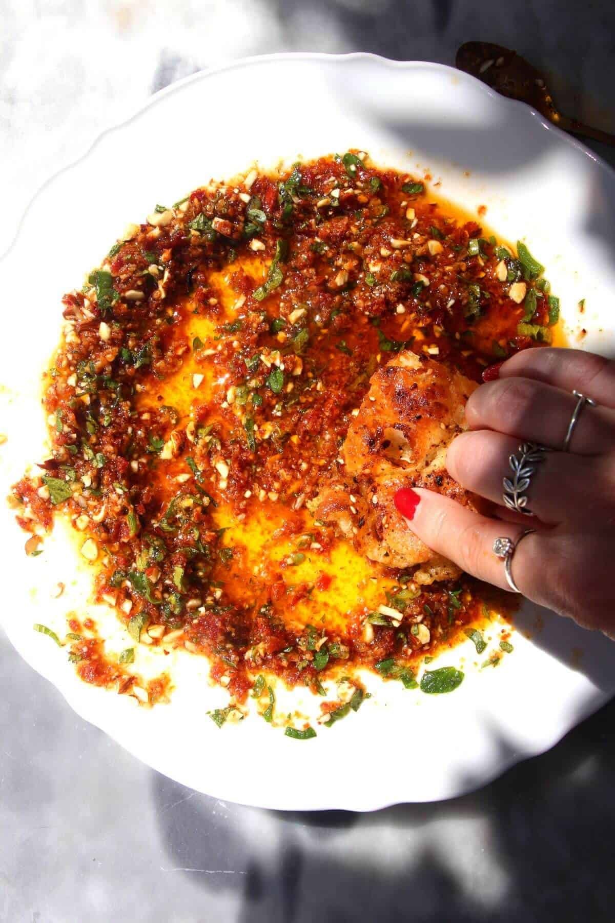 Hand swirling bread through sundried tomato dipping oil.