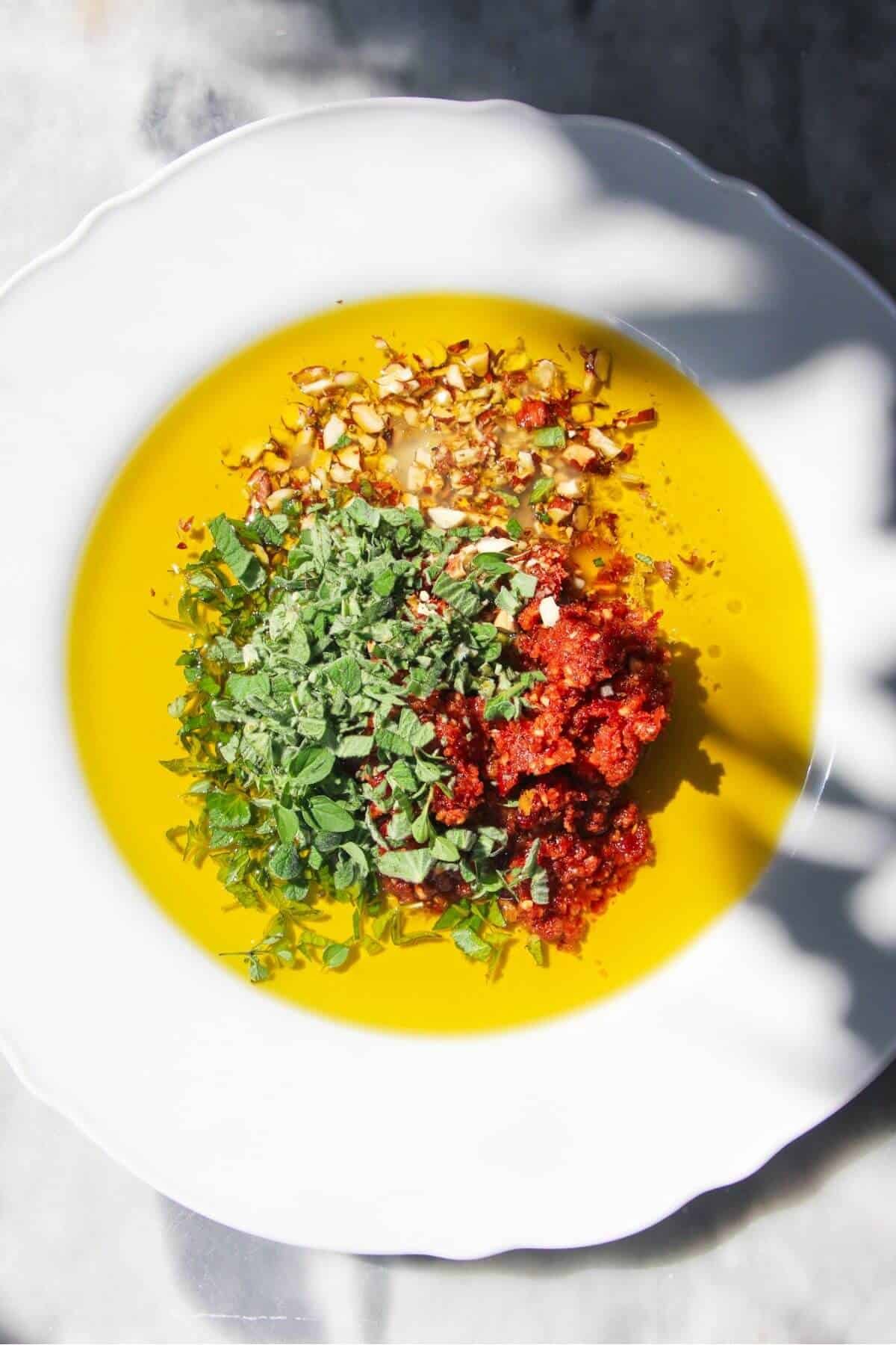 Ingredients for sundried tomato dipping oil on a white plate.