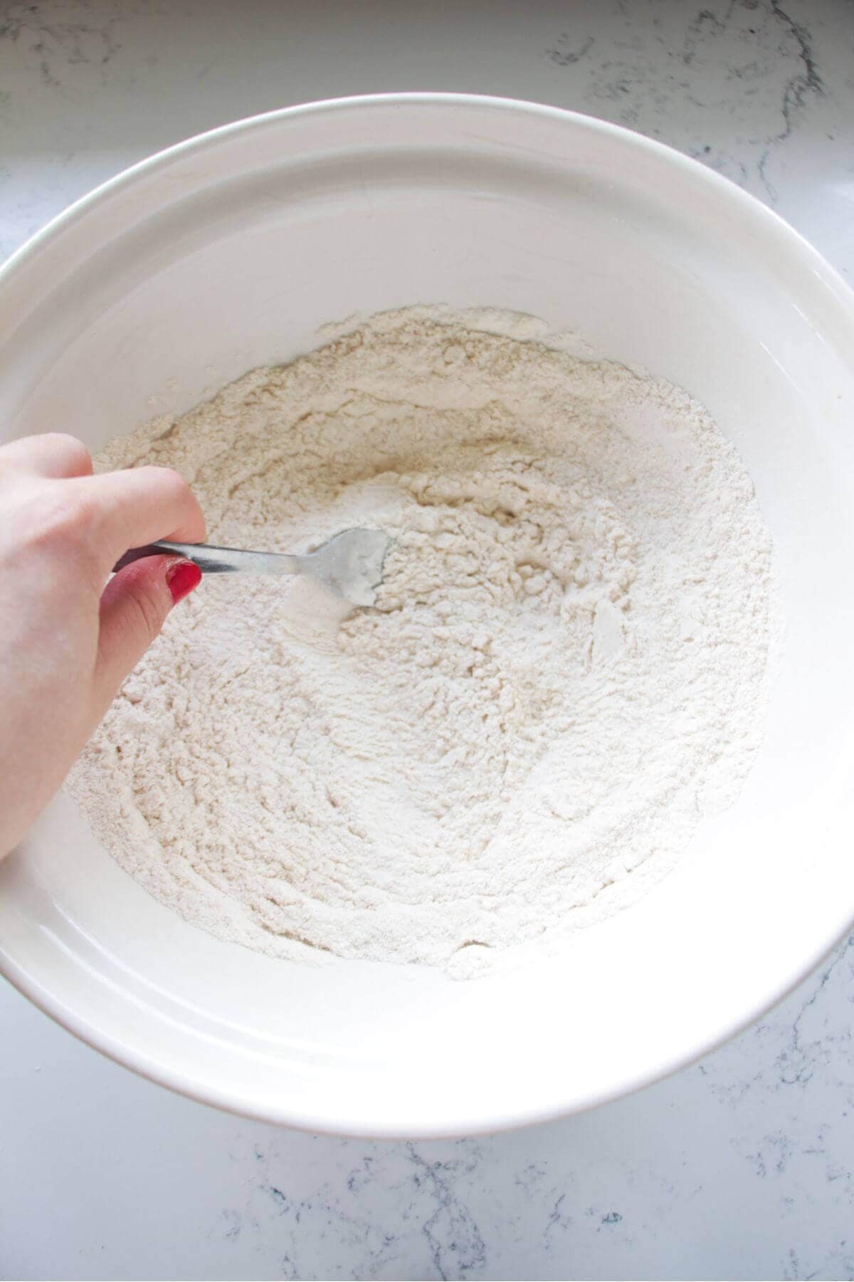 Fork mixing flour and spices for the fried chicken coating.