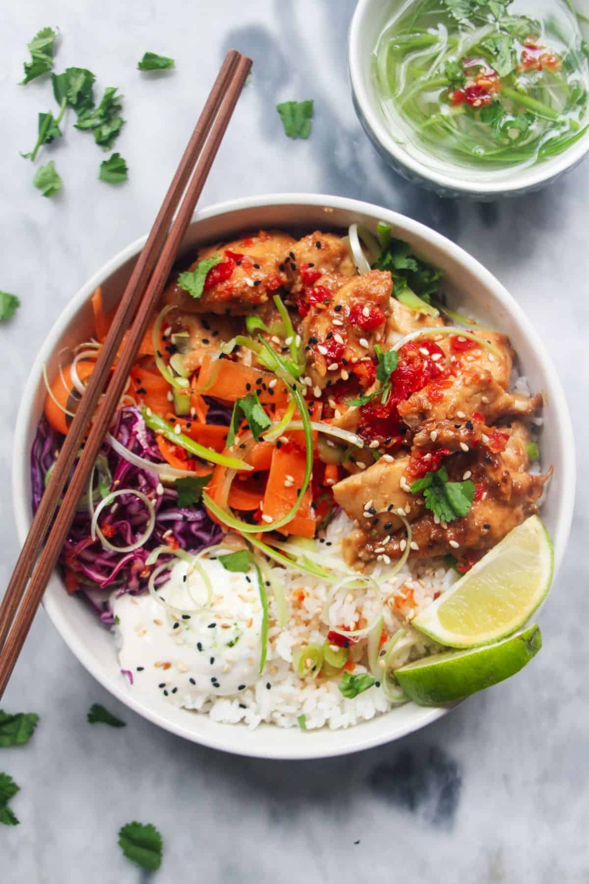 Grilled chicken poke bowl on a grey marble background.