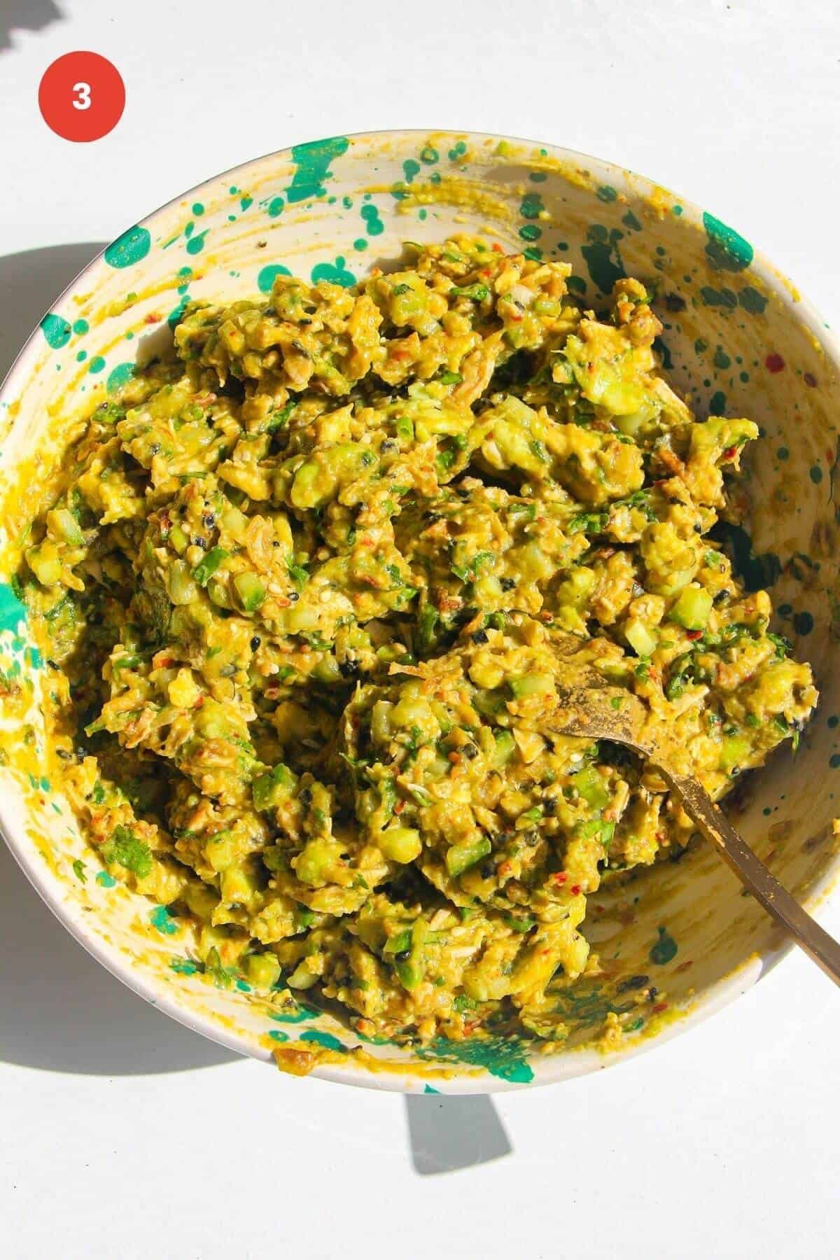 Avocado, cucumber, scallions and chicken mixed in a bowl.