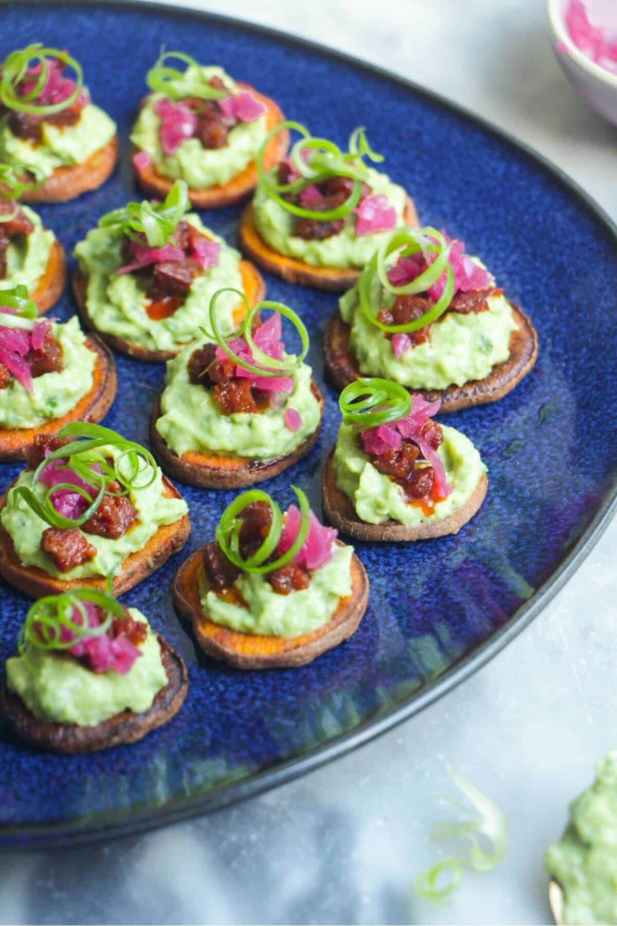 Loaded sweet potato bites on a large blue plate.
