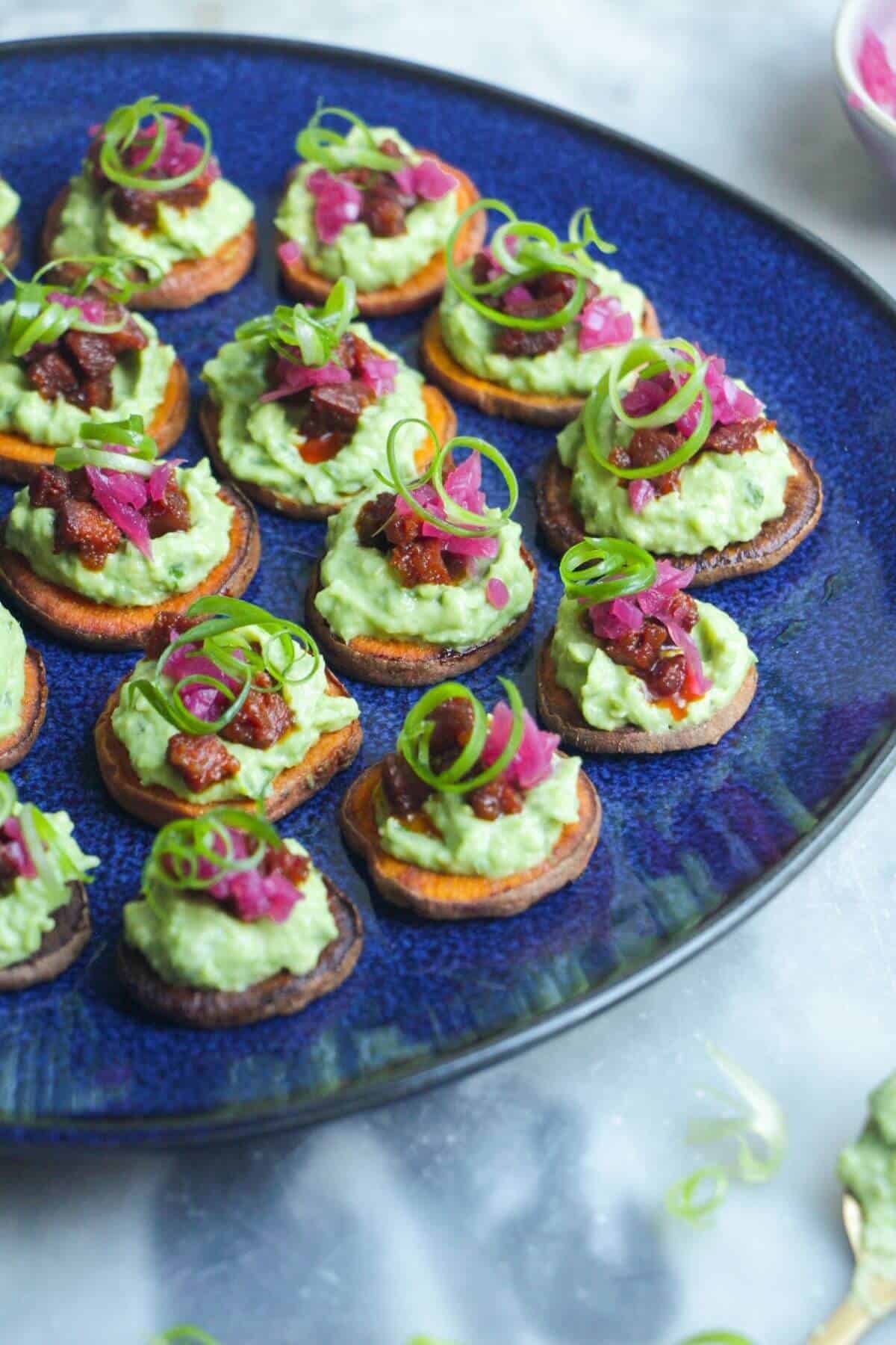 Loaded sweet potato bites on a large blue plate.