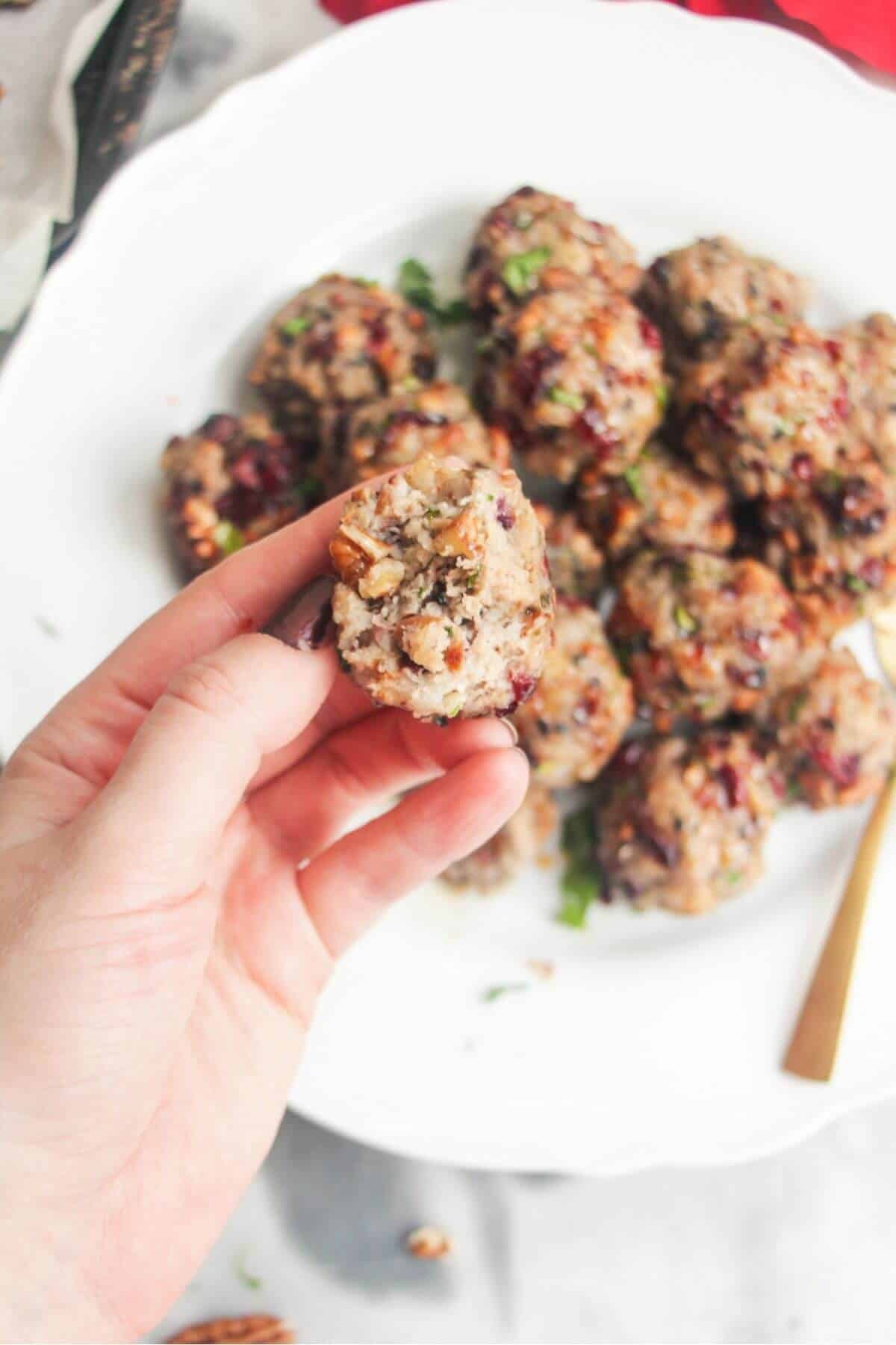 Hand holding a torn open stuffing ball with more stuffing balls in the background.