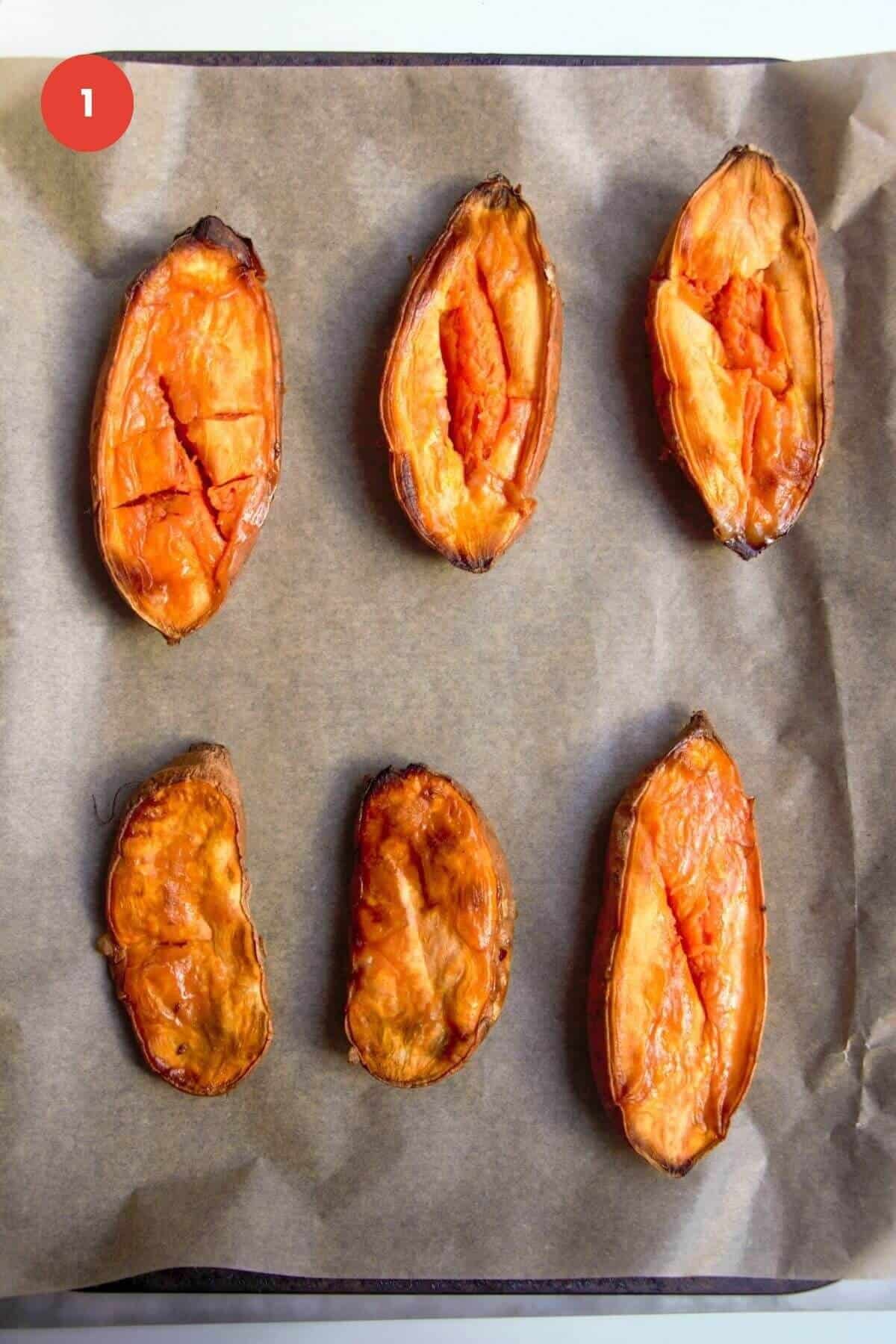 Roasted sweet potato halves on a lined oven tray.