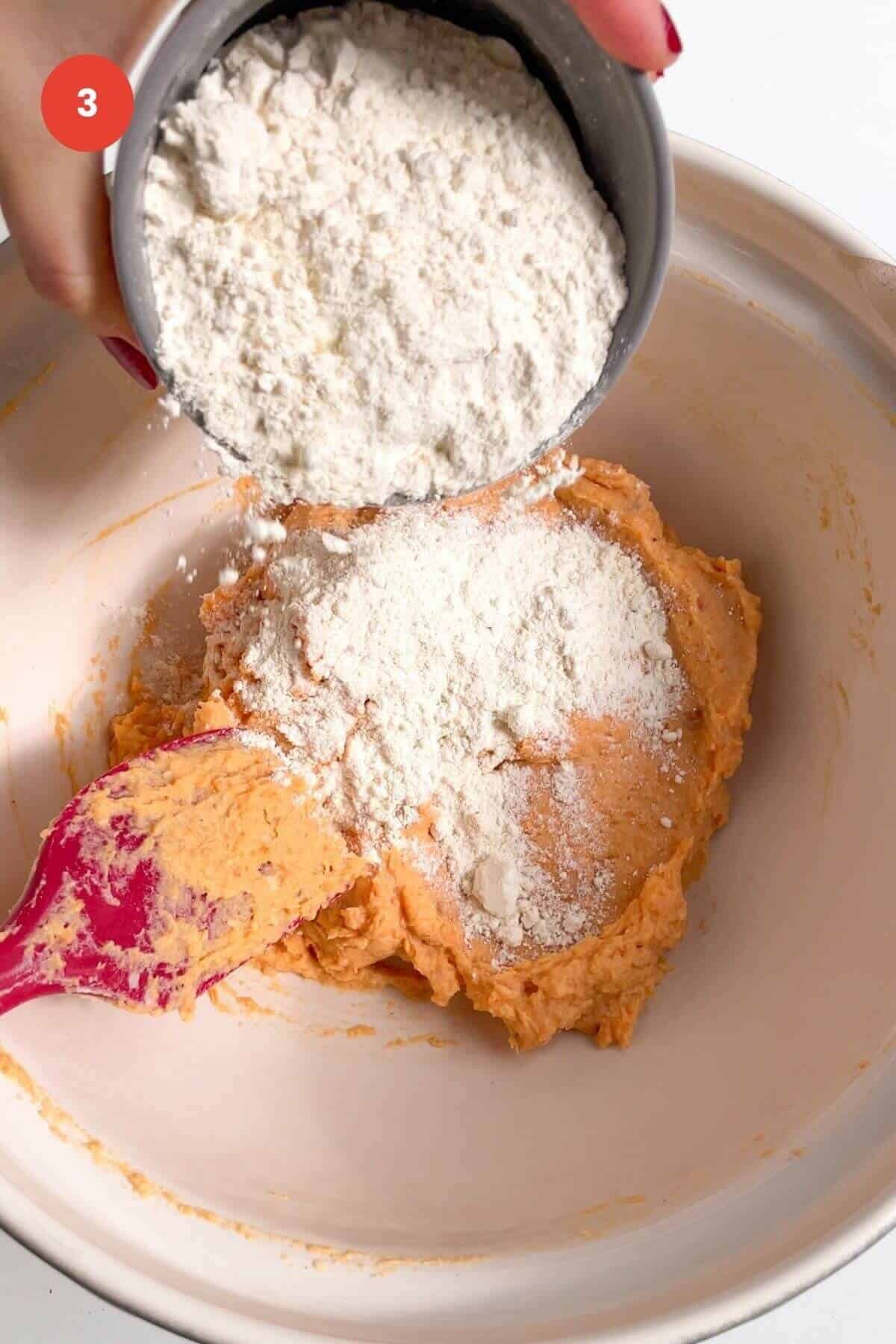 Flour being added to sweet potato gnocchi dough in mixing bowl.