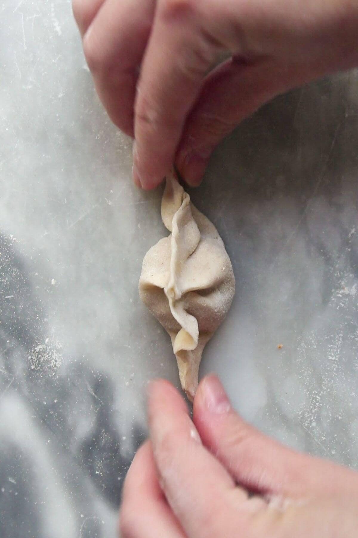 Hands folding a dumpling.