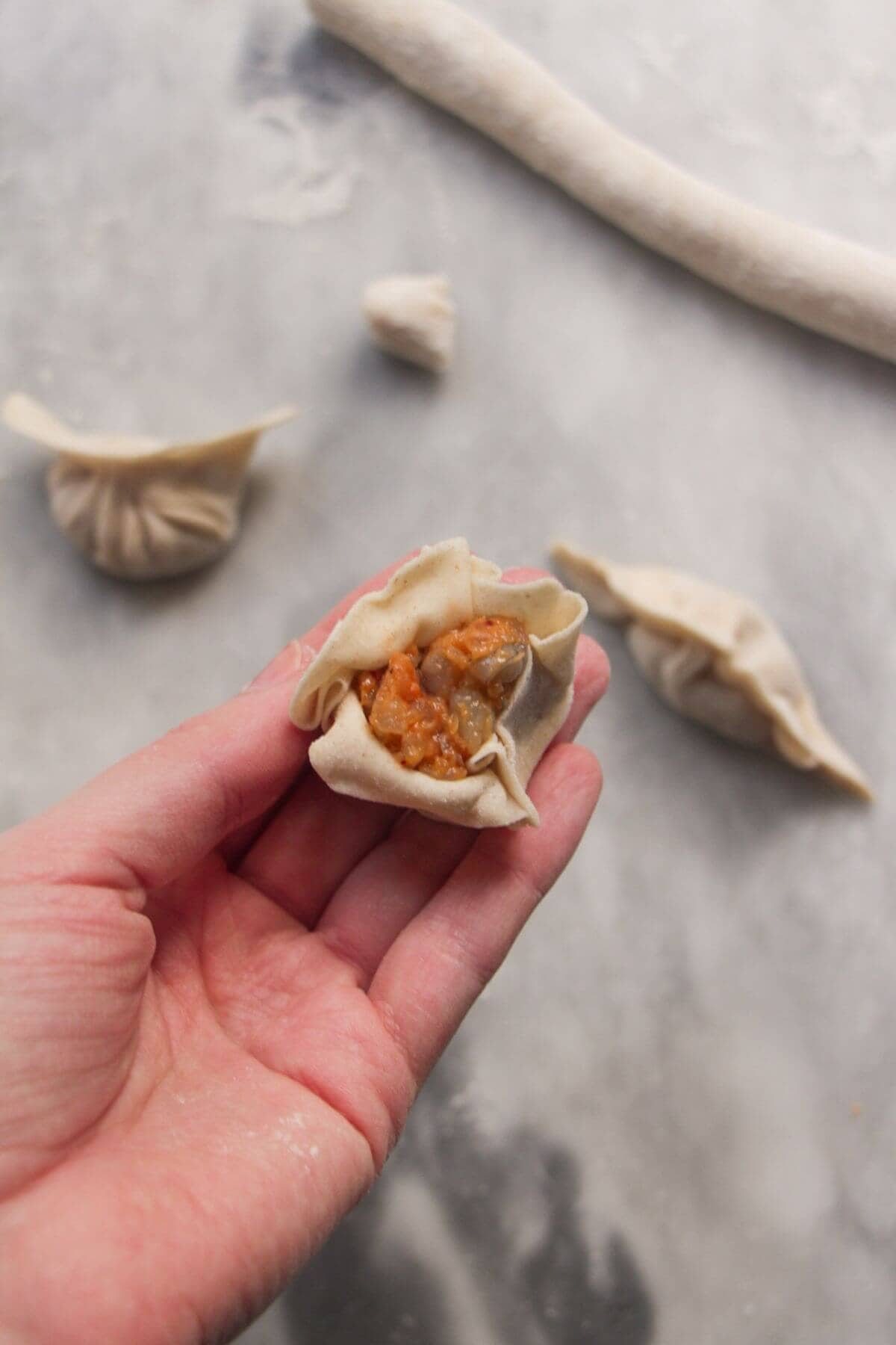 Hand holding siu mai shaped dumpling.