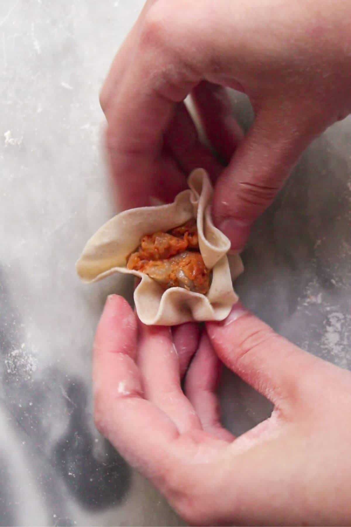 Hands folding a dumpling.