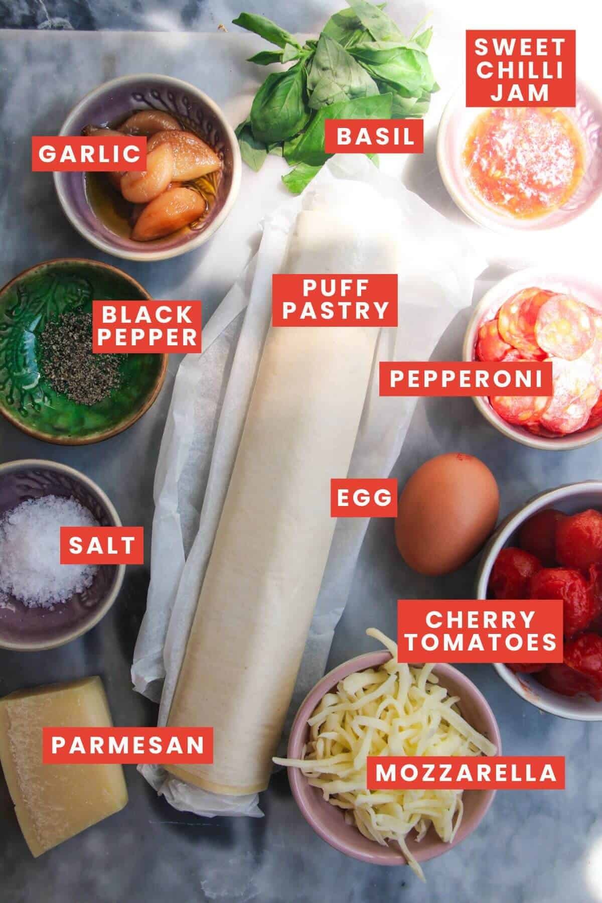 Ingredients for upside down puff pastry tarts laid out on a grey marble background and labelled.