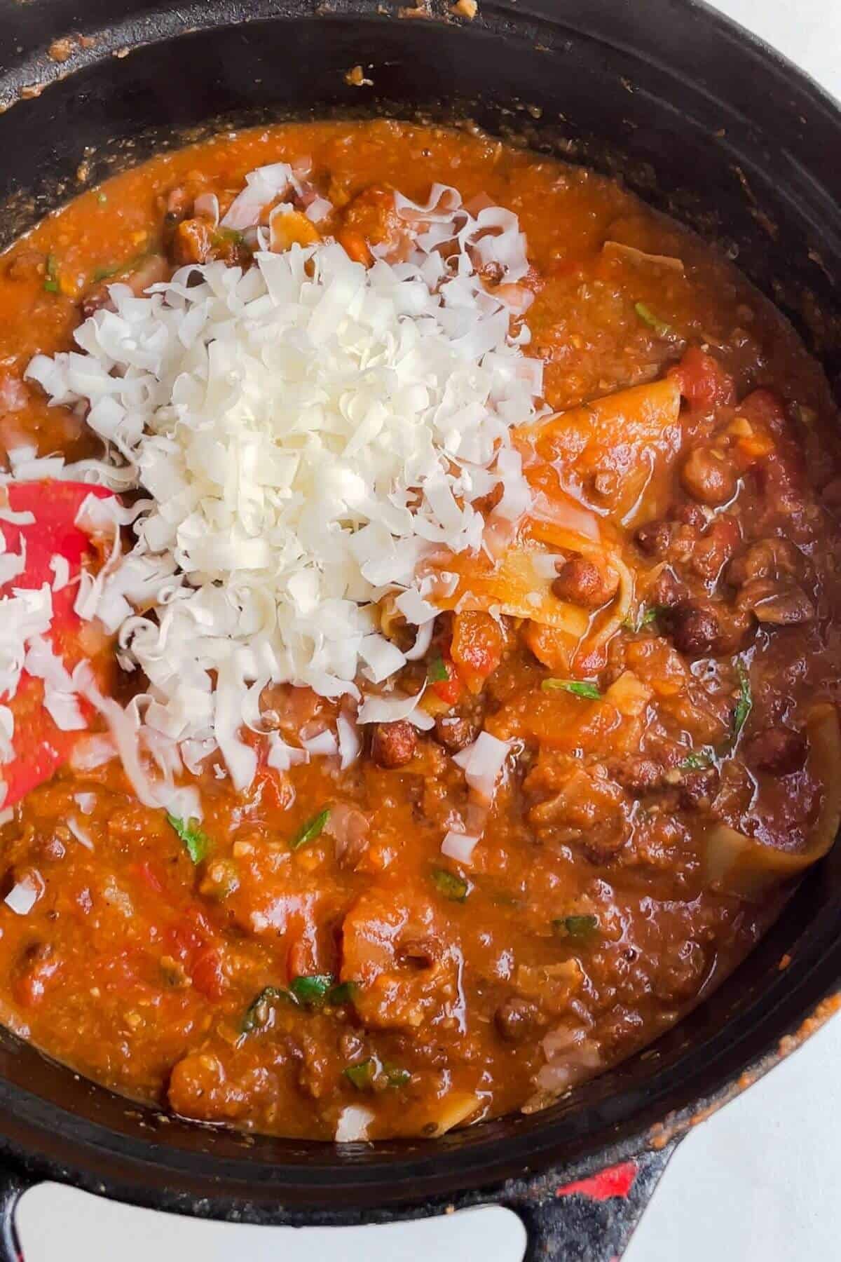Grated parmesan added to lasagna soup in a large bowl.