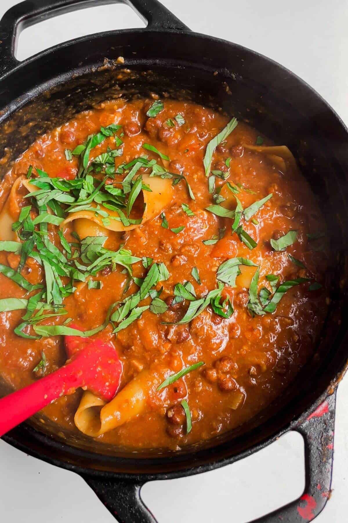 Sliced basil leaves added to soup in a large pot.